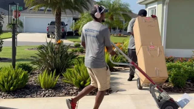 Mover transporting a large boxed item on a dolly during a residential move in Florida