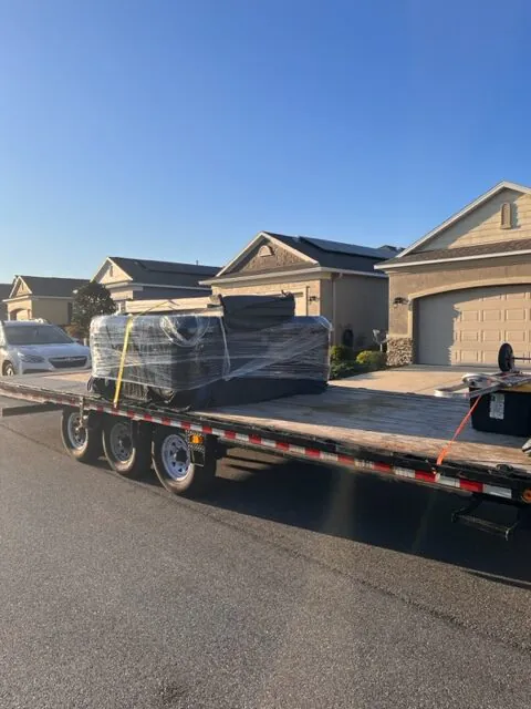 flatbed truck transporting wrapped furniture and household items during a long distance move in Florida neighborhood